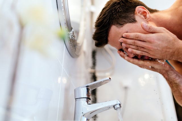 man washing face in morning and practicing hygeine