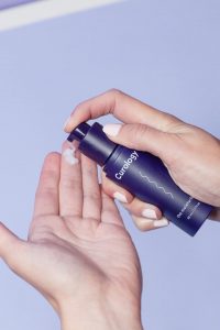 person holding curology spray bottle