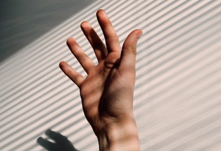 persons hand on white window blinds