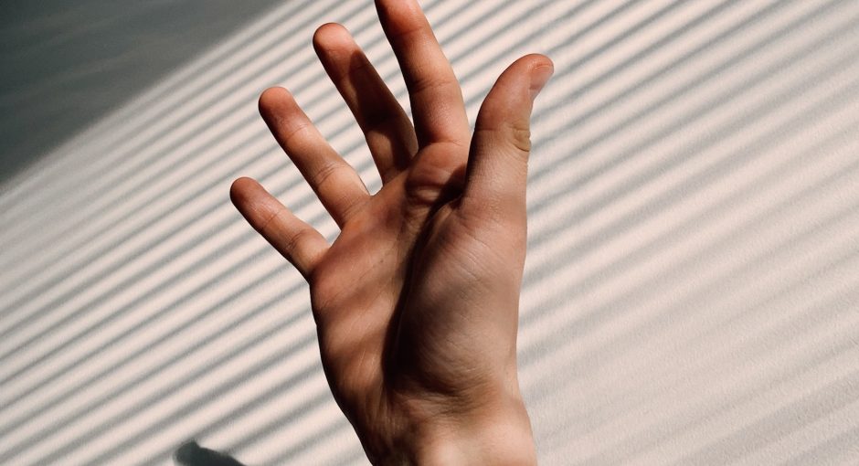 persons hand on white window blinds