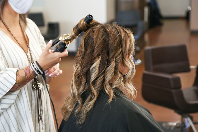 woman in black long sleeve shirt holding curling iron